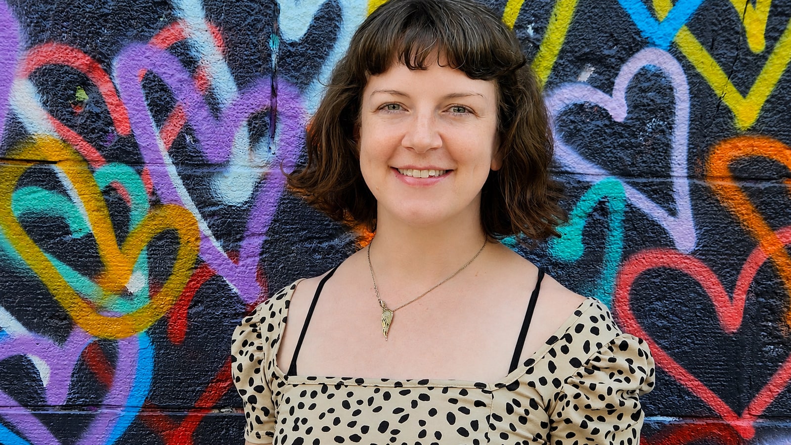Katie O'Connor in front of a graffiti mural.